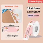 Étiquette rose à arc-en-ciel et nuages souriants, déclinée en onglets sur un carnet, avec son rouleau de 160 étiquettes