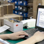Poste d'expédition en entrepôt avec imprimante thermique blanche, ordinateur portable et cartons