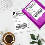 Étiquette d'expédition et pochette d'envoi rose posées sur un bureau blanc, près d'un clavier