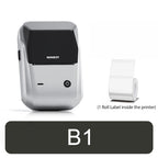 Imprimante compacte blanc argenté à capot noir brillant, vue de trois quarts devant un petit rouleau d'étiquettes