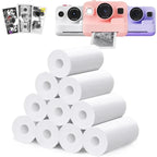 Rouleaux de papier thermique blanc empilés devant trois appareils photo instantanés blanc, rose et violet