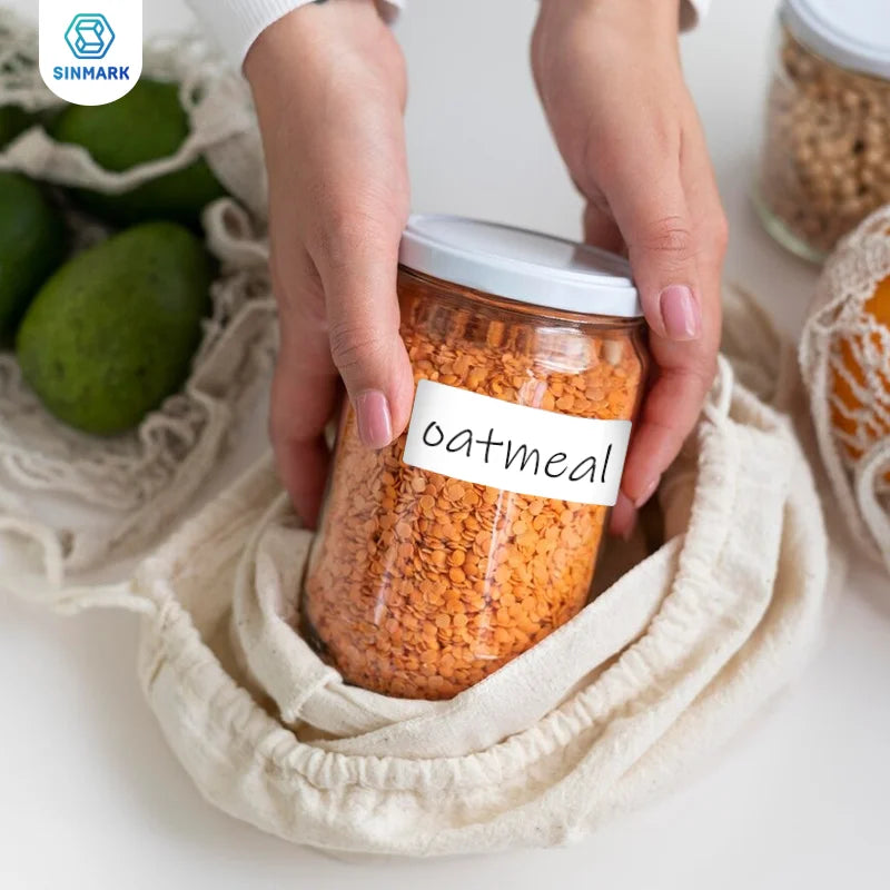 Mains rangeant un bocal de lentilles corail étiqueté oatmeal dans un filet en coton, en cuisine