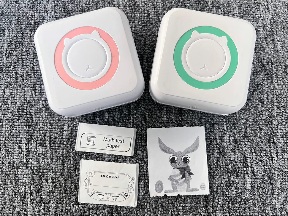 Imprimantes à anneau rose et à anneau vert sur moquette grise, avec un ticket Math test paper, une TO DO List et un lapin imprimé